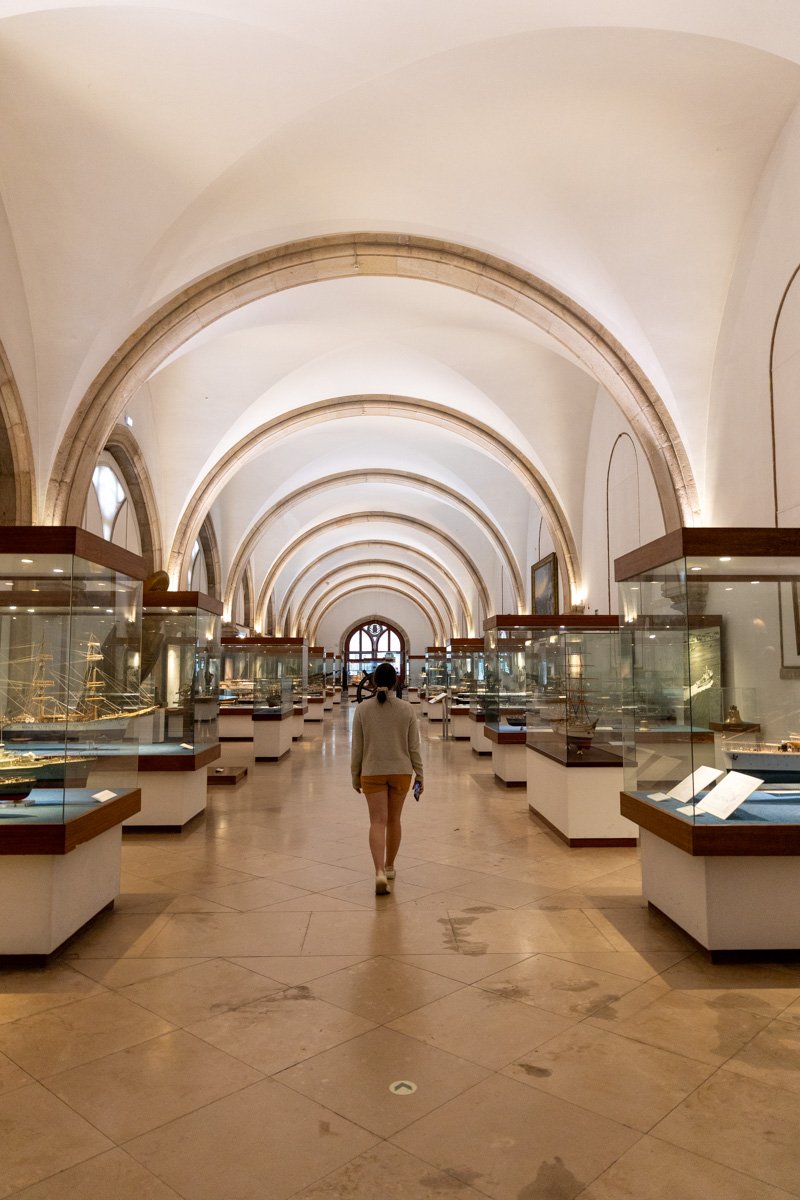 Une femme qui marche dans un grand hall vouté avec des vitrines