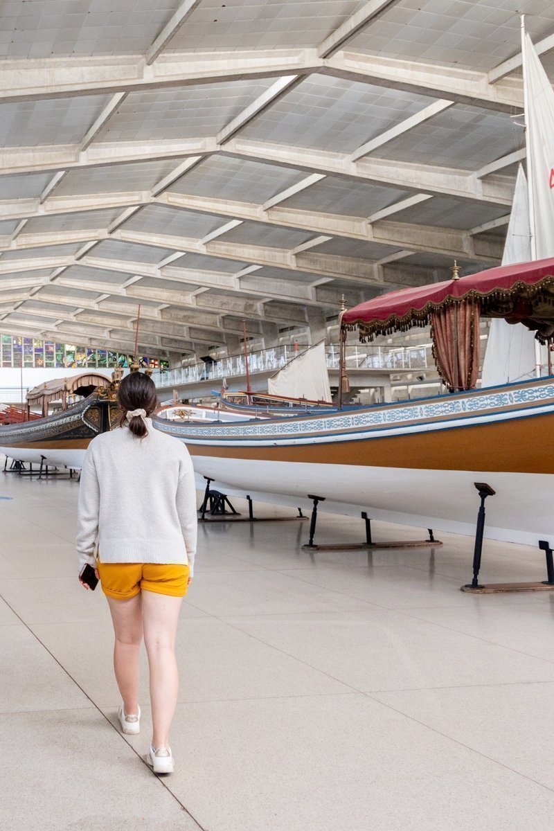 Personne qui marche entre des bateaux exposés dans un grand hall